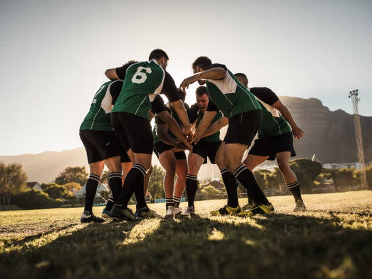 A sports team huddle on the field at sunset